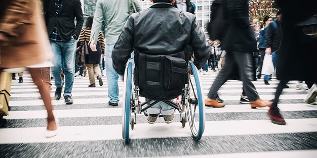 En person som tar sig fram i rullstol. Foto