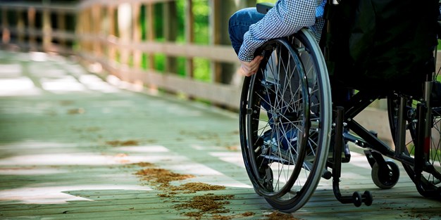 Person i rullstol på asfalt. Foto