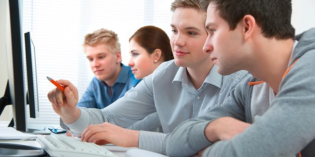 Two students sitting and working on a computer. Photo