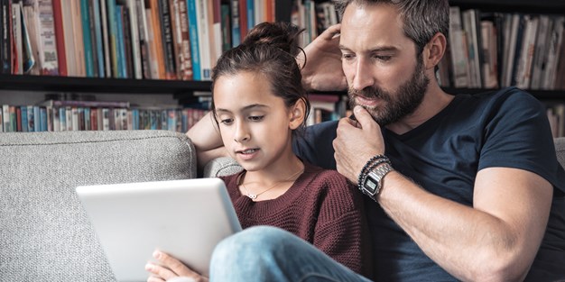 Daughter and father use a tablet. Photo