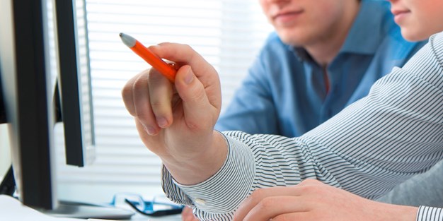 A person pointing at a computer screen with his pen. Photography