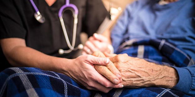 En sjuksköterska besöker en äldre patient. Foto