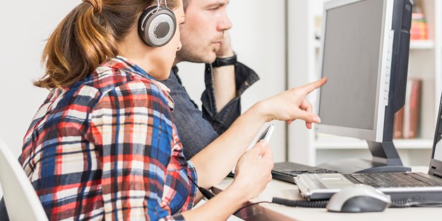 Two people work on a computer. Photo