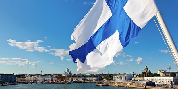 Den finländska flaggan som vajar i vinden. Foto