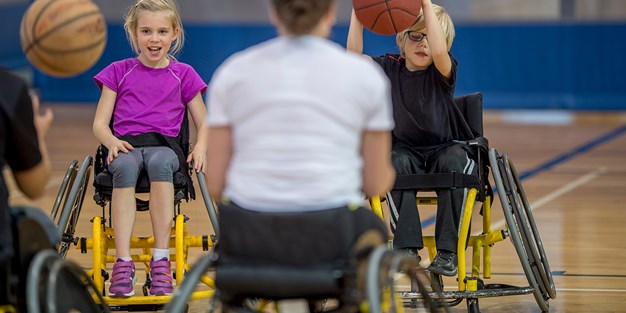 Barn spelar rullstolsbasket. Foto