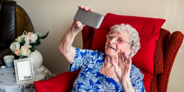 En äldre person som tar en selfie med en smartphone. Foto