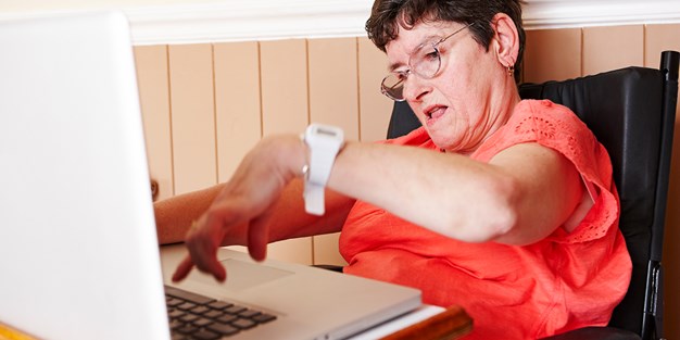 Person med nedsatt funksjonsevne som arbeider på en PC. Foto