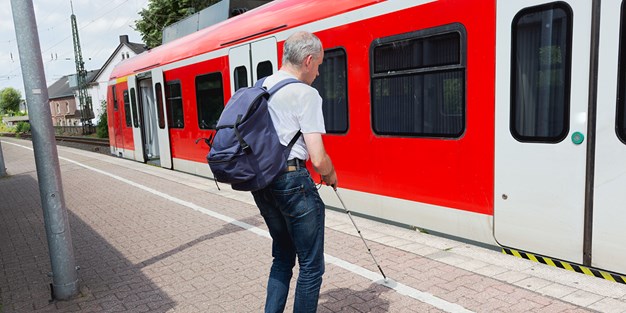 En blind person som ska stiga på ett tåg. Foto